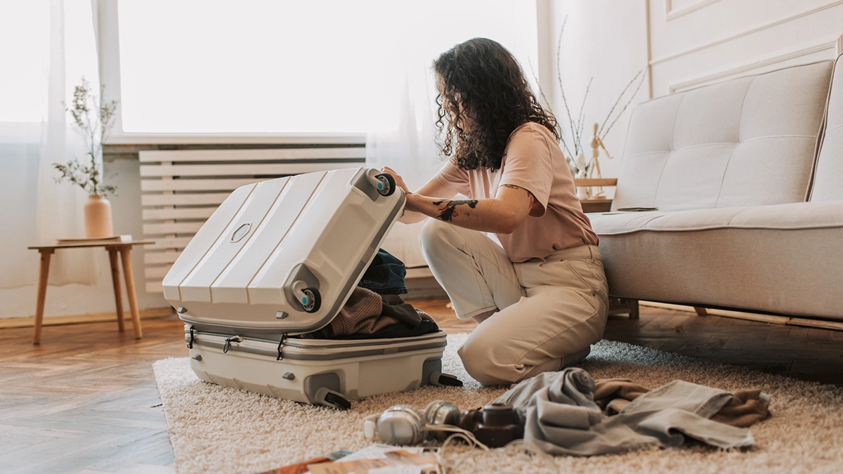 Woman packing a suitcase with clothing and camp essentials before Camp Sober Fest